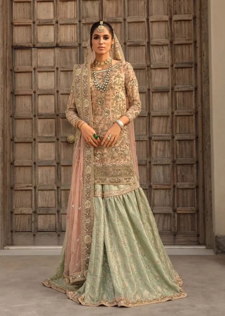 A bride wearing a pastel pink chiffon Nikah dress with delicate lace detailing.
