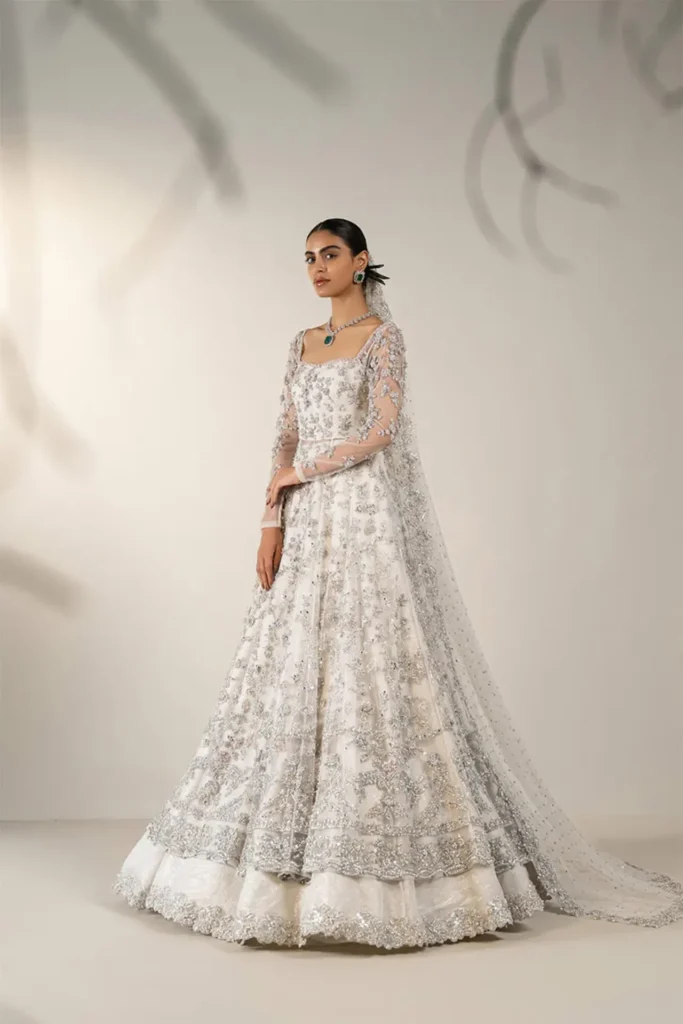 A bride wearing a pastel pink chiffon Nikah dress with delicate lace detailing.
