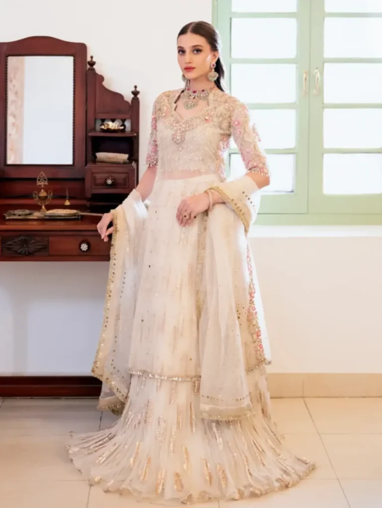 A bride wearing a pastel pink chiffon Nikah dress with delicate lace detailing.
