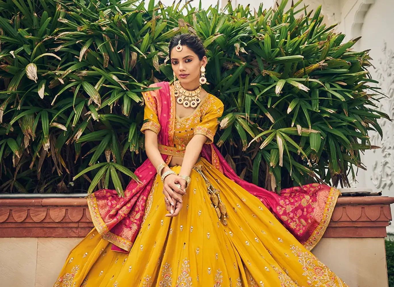 Bride wearing a vibrant pink ghagra choli with mirror work at a Sangeet ceremony.