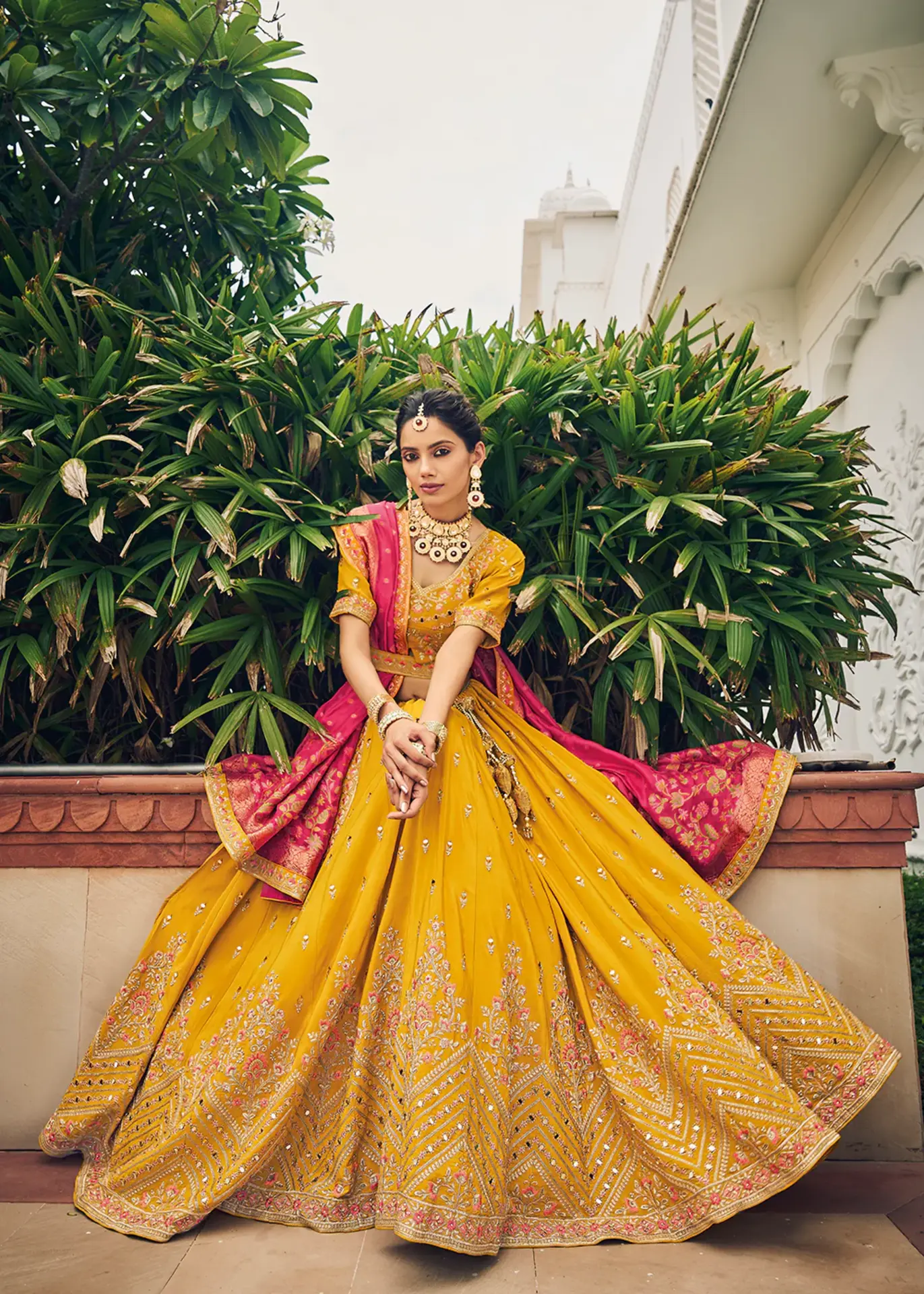 Bride wearing a vibrant pink ghagra choli with mirror work at a Sangeet ceremony.